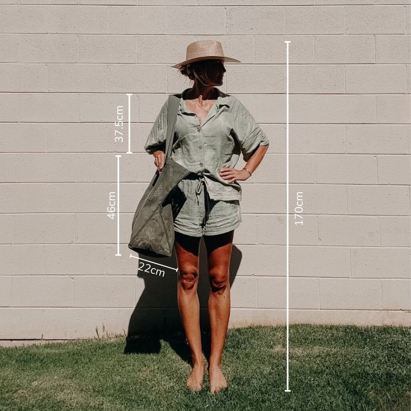 Model 170cm tall holding a Sande Beach Hauler Mini mesh beach bag in a pandanus green.