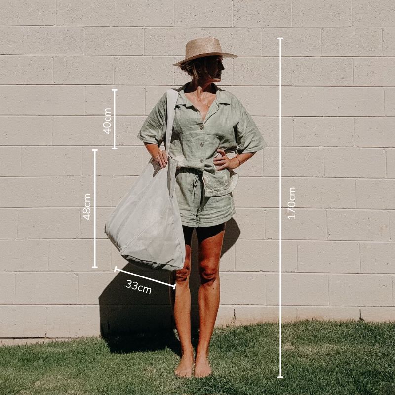 Woman 170 cm tall modeling the original Sande™ Beach Hauler mesh beach bag in Sand colorway. This stylish and spacious neutral beach bag is designed for functionality, making it perfect for family outings and big beach adventures.