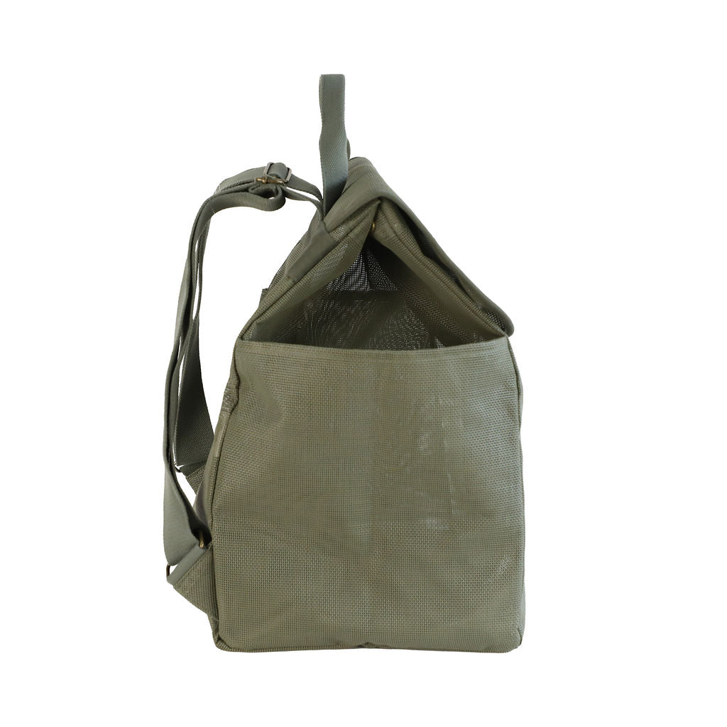 A studio image of the Sande Beach Hauler mesh backpack in Pandanus Green, shown from the side to highlight its spacious design and practical features. This side view emphasises the large side mesh pockets, adjustable straps, and the handle at the top. The backpack is set against a white background, showcasing its durability and ideal design for beach trips and outdoor adventures.