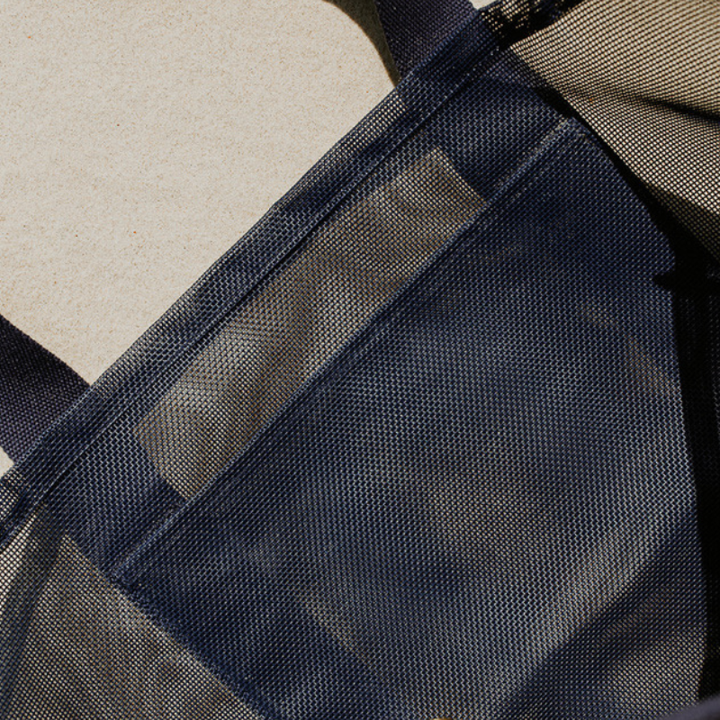 Close-up of the high-quality features of the Sande Beach Hauler mesh beach bag in Deep Sea Navy. Showcases the large internal mesh pocket for extra storage, along with the durable PVC mesh fabric and thick cotton straps.