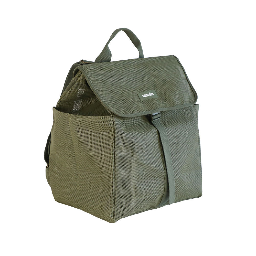A studio image of the Sande Beach Hauler mesh backpack in Pandanus Green, displayed at a 45 degree angle to highlight its functional design. This view showcases the flap with a plastic clip, adjustable straps, large side mesh pockets, and a convenient handle at the top. The backpack is set against a clean white background, emphasising its durability and practicality for beach adventures.