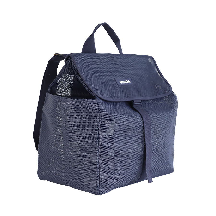 This studio image shows the Sande Beach Hauler mesh backpack in Deep Sea Navy at a 45-degree angle. The front view highlights key features, including a top carry handle, two side mesh pockets, a flap with a clip for added security, and a silicone label with the Sande logo in white.