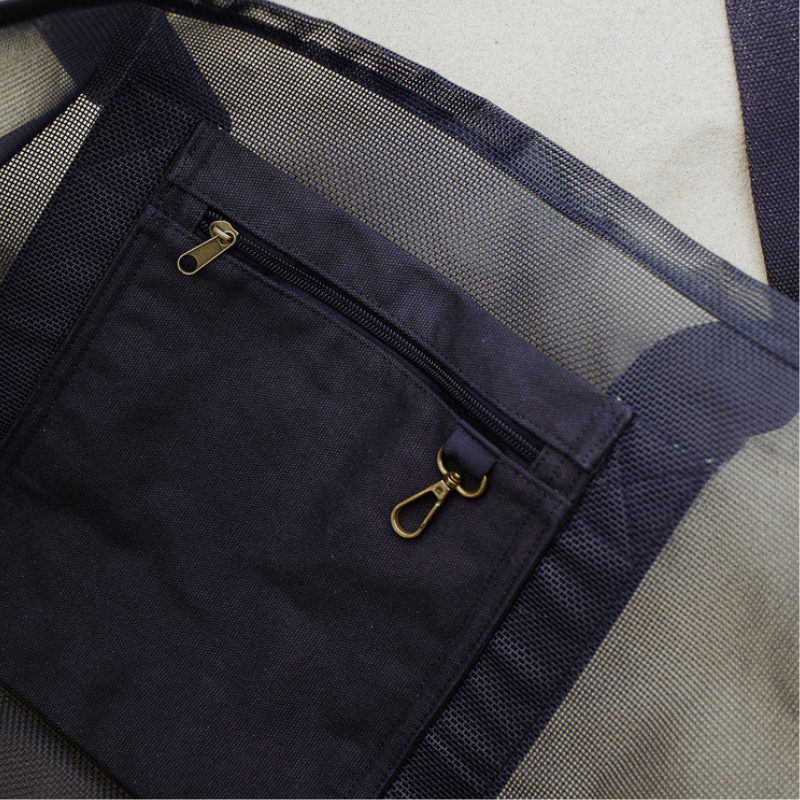 Close-up of the high-quality features of the Sande Beach Hauler - Mini mesh beach bag in Deep Sea Navy. Showcases the internal canvas pocket for valuables and a handy key clip, along with the durable PVC mesh fabric and thick cotton straps.