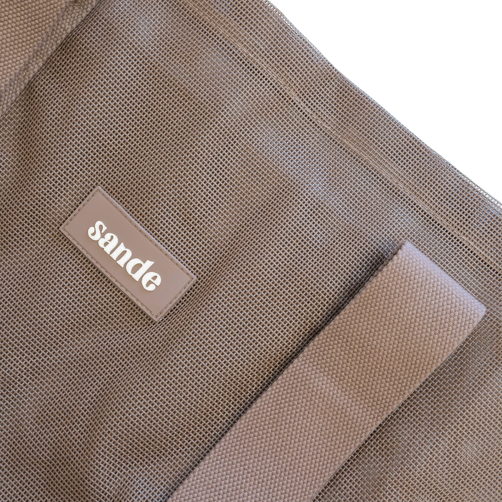 Close-up image of the Sande™ Beach Hauler Mini mesh bag in Espresso Brown, highlighting the durable mesh fabric, thick cotton straps, and silicone Sande logo. Perfect for carrying beach essentials on family beach days, market trips, and outdoor adventures.