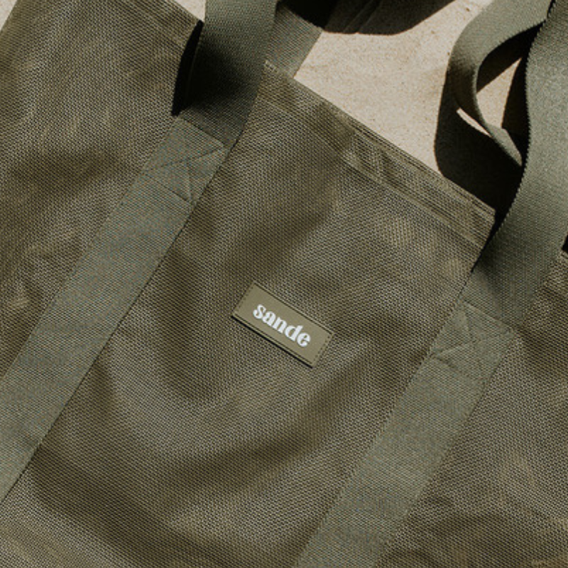 Sande original mesh beach bag in Pandanus green showcasing silicone label feature.