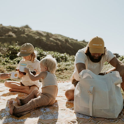 Dad and  enjoying a picnic at Cabarita Headland, with dad using the Sande  Beach Hauler mesh backpack in Sand colour.